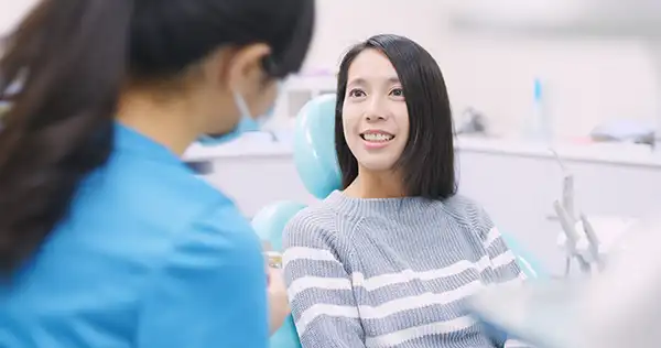 A masked dentist consults with a female patient.