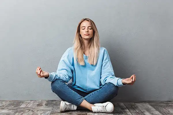A young woman in a blue sweater meditating