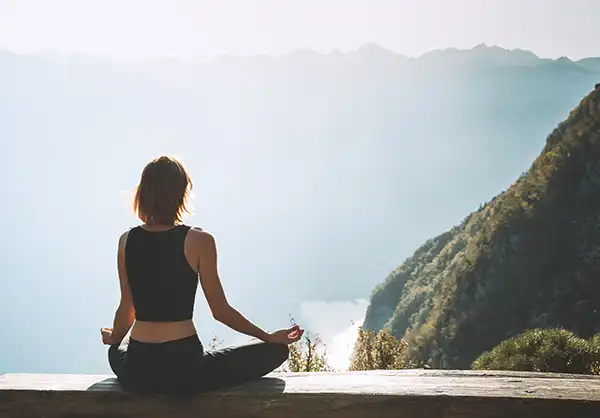 A woman meditating at a beautiful vista