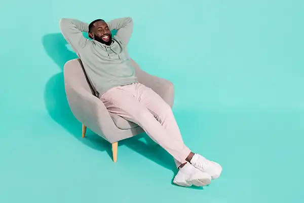 A man smiling, relaxing and reclining back into chair
